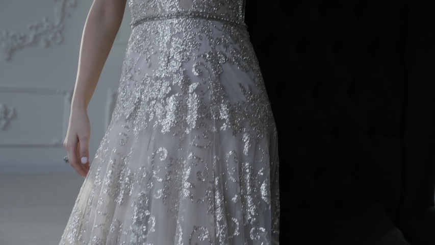 smart lady with plump lips loose hair in long wedding dress stands at vintage wall low angle shot closeup slow motion