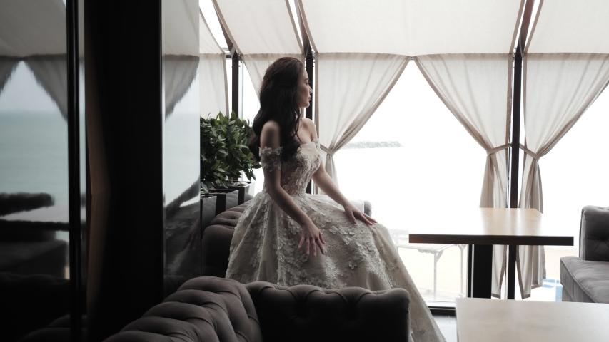 beautiful long haired woman demonstrates stylish lacy wedding dress in restaurant lounge slow motion
