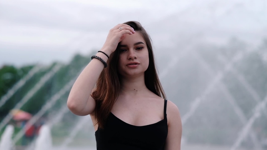 Beautiful young girl with dark hair at the fountain. Slow motion