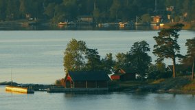 An beautiful summer evening aerial footage of Nordic coastline coast showing trees, houses and pier. Filmed in Full HD slow motion with a large telephoto zoom lens.