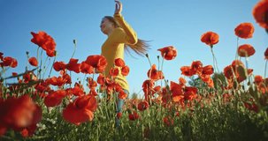 Beautiful girl with long hair having fun outdoors in the poppies field. Slow motion 120 fps. Filmed in 4K DCi resolution. Happy smiling young woman enjoying nature. Crane shot.
