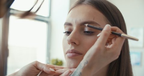 Microblading, micropigmentation eyebrows work flow in a beauty salon. Woman having eye brows drawn and tinted with pencil, preparing for semi-permanent makeup . 4K slow motion raw video footage 60 fps