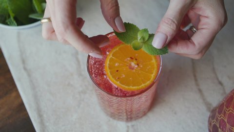 Top view of hands gently placing mint leaves as a garnish on a cocktail for food photography. Shot on a Canon C200 in 4K in Phoenix, Arizona in 2019.