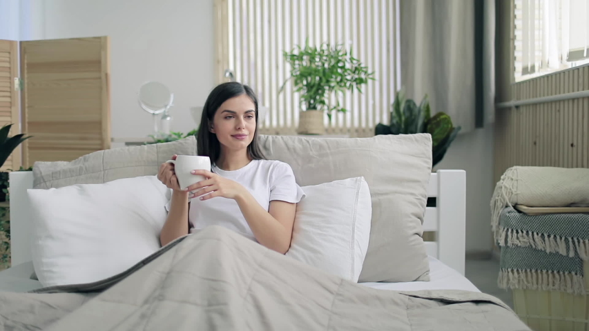 Beatiful brunette girl using futuristic hologram hud panel screen for browsing internet while lying in the bed in the morning Royalty-Free Stock Footage #1030810775