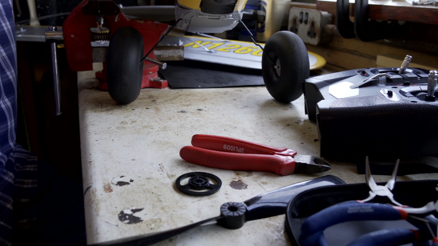 Senior Man Working On Model Radio Controlled Aeroplane In Shed At Home                               