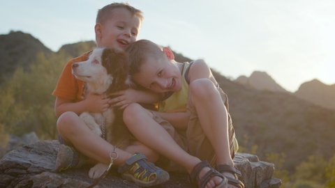Two young boys hug their puppy outside at sunset. Shot on a Canon C200 in 4K in Phoenix, Arizona in 2019.