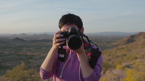Proud photographer holding a camera and taking pictures by sunset in the desert. Shot on a Canon C200 in 4K in Phoenix, Arizona in 2019.