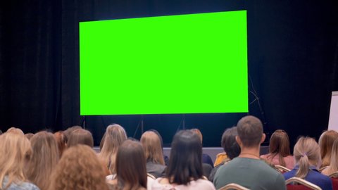 Session or debate of people in large class room. Modern cinema space for watching movies with display or monitor at background. Humanity are watching a film or a new product show on TV air events