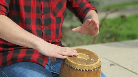 Close-up of guy in plaid shirt beating on drum