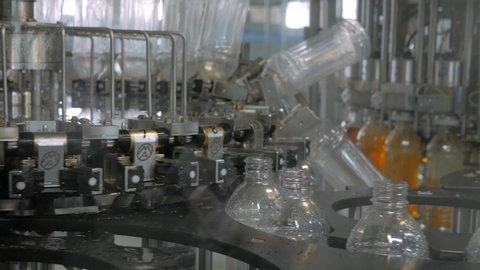 Plastic bottles inside industrial machine conveyor line or belt preparing for filling with drink. Water and juice bottling plant.