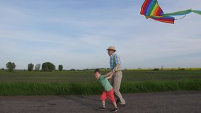 Side view of active grandfather and grandson running with kite along country road among spring fields. Cute little boy having fun holding flying kite and grandpa's hand enjoying outside leisure - Powered by Shutterstock - Get 15% off with code: PIKWIZARD15
