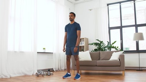sport, fitness and healthy lifestyle concept - indian man doing jumping jack exercise at home