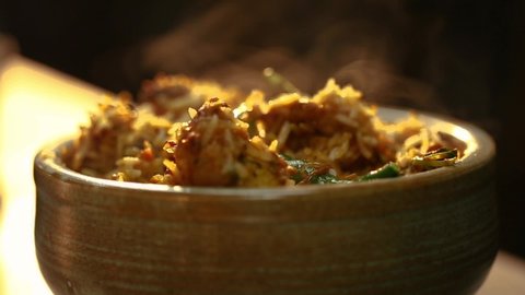 Closeup shot of serving biryani in bowl.Garnishing biryani with coriander leaves.Closeup shot of serving biryani in bowl.Delicious biryani served for lunch/dinner.