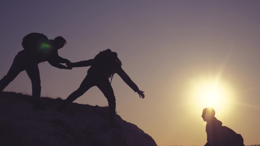 teamwork help business travel silhouette concept. group team of tourists lends helping hand climb the cliffs mountains. teamwork people climbers climb to the top helping hand hardships the path  Royalty-Free Stock Footage #1030849778