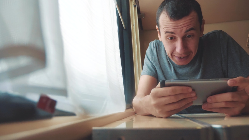 man playing an online game on a smartphone, strong emotions, anger man sitting in a train by the window. slow motion video. train emotions joy surprise lifestyle journey concept - Powered by Shutterstock - Get 15% off with code: PIKWIZARD15