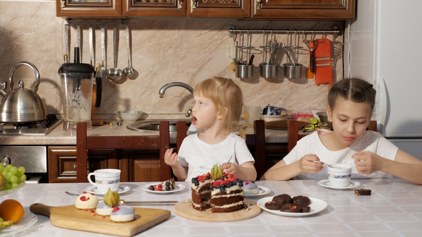 Family birthday at home, mother wipes her dirty little daughter face with a napkin during tea at the table. Parent care about her child.