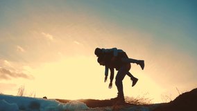 father and daughter teamwork happy family tourists silhouette concept rides on his back funny video . team dad and daughter on sunset play dabble the top of the mountain with backpacks. winning