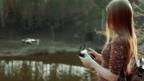 Young Happy Girl With Remote Control Controls the Quadcopter Drone on Field During Sunset
