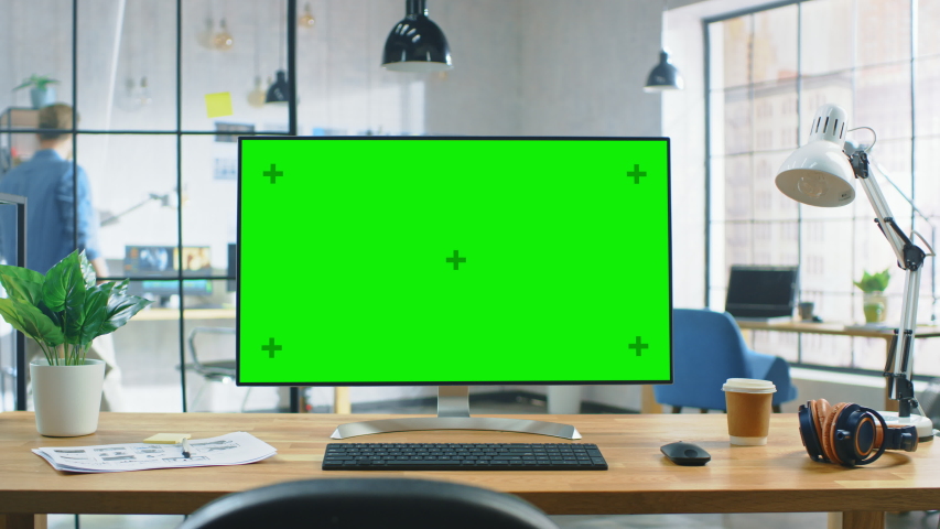 Wide Green Mock-up Screen Desktop Computer Standing on the Desk in the Modern Creative Office. In the Background Bright Creative Loft for Developers and Designers where Professional Working Royalty-Free Stock Footage #1030863458