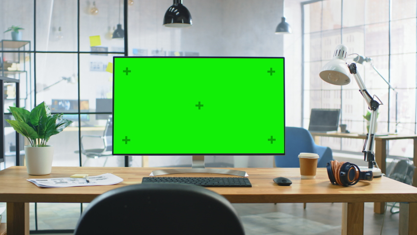 Wide Green Mock-up Screen Desktop Computer Standing on the Desk in the Modern Creative Office. In the Background Bright Creative Loft for Developers and Designers where Professional Working. Zoom In Royalty-Free Stock Footage #1030863467