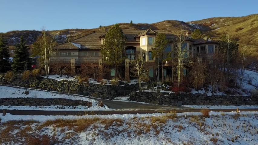 AERIAL: lifting up past a beautiful home, following the mountain side, within the Rocky Mountains in Colorado.