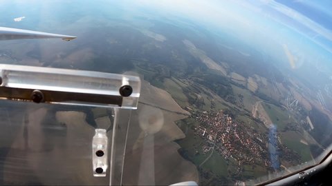 pilot's point of view from a cockpit of a sailplane while detaching a towrope above fields and forests, ponds and villages