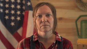 American farmer reviewing peat pot for her vlog, headshot of adult female person in plaid shirt with USA flag in background