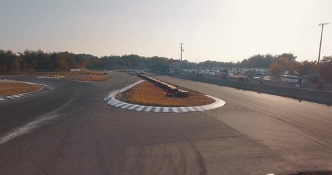 Low Aerial Drone Shot of Import Race Cars Speeding and Drifting Around a Curve on a Race Track.