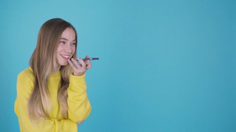Indoor portrait of attractive young european woman isolated on color background, holding blank smartphone, using voice control, feeling happy and surprised. Human emotions, facial expression . 4K