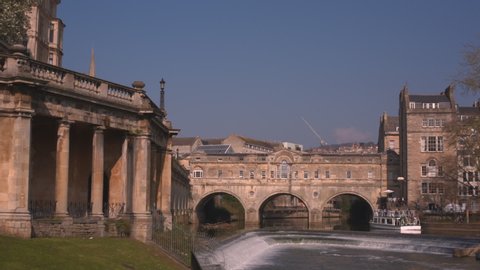 Tourist boat enters arches under Pulteney Bridge on the Avon river in the historic Roman city of Bath Spa in England