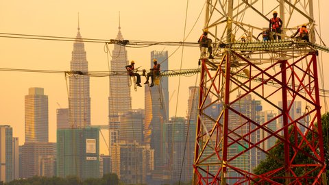 Time lapse of electricians in silhouette working on a new power transmission tower as part of the nation power grid. Dramatic scene. Kuala Lumpur, Malaysia