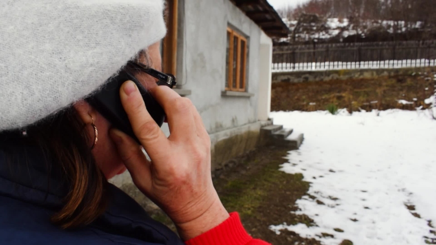 Woman with beret on head talking on old mobile phone