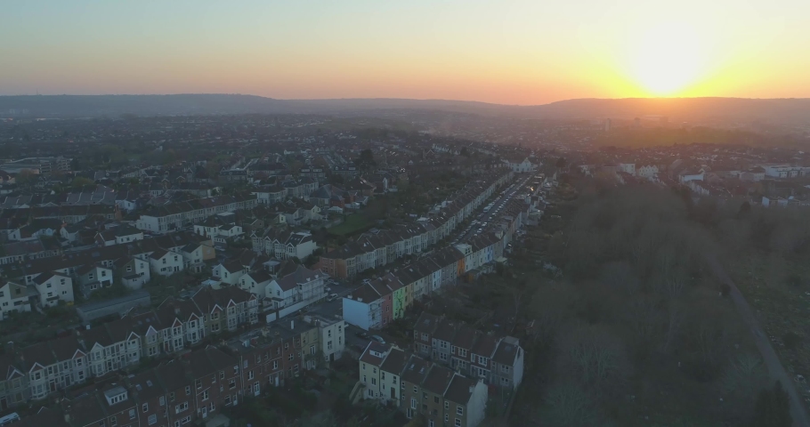 Aerial flying past rows of coloured terraced suburban houses towards the setting sun in Bristol UK Royalty-Free Stock Footage #1030893725