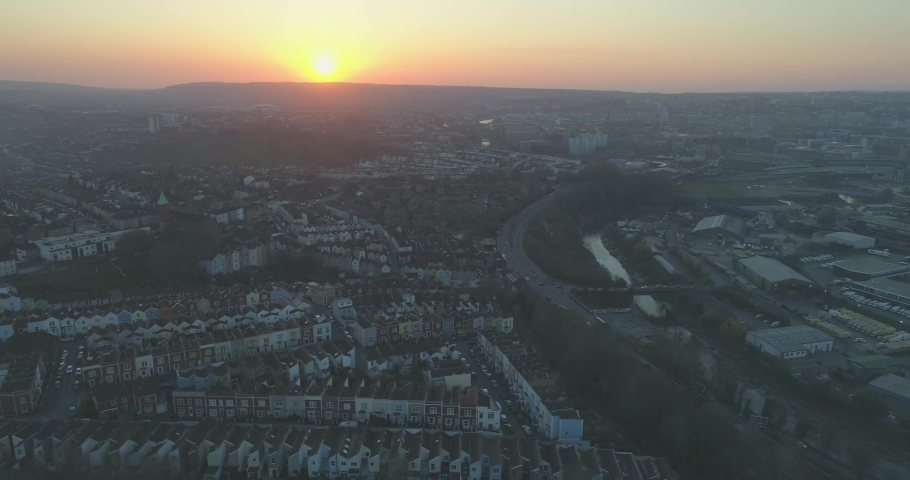 Wide aerial tracking past rows of coloured terraced suburban houses in South Bristol UK with the setting sun in the background Royalty-Free Stock Footage #1030893734