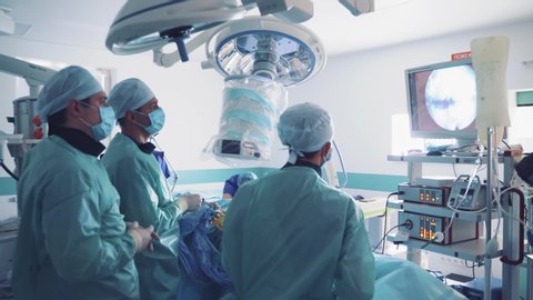 VINNITSA, UKRAINE - MAY 2019: Hospital teamwork profession job. Surgeon analyzing patient heart testing result and human anatomy on technological digital interface