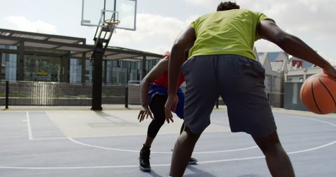 Front view of African american basketball players playing basketball in basketball court. They are dodging basketball
