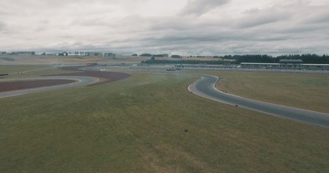 Wide Aerial Drone Shot Following Behind Two Speeding Race Cars as they Drift Around a Race Track.
