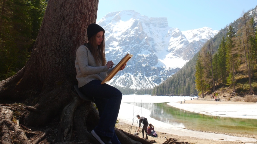 Dolomites. A young woman drawing on a canvas in nature