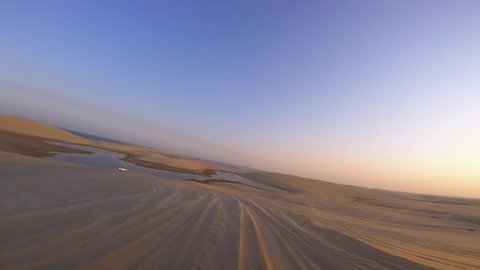 First person view, POV video as smoothly driving through huge sand dunes in a desert