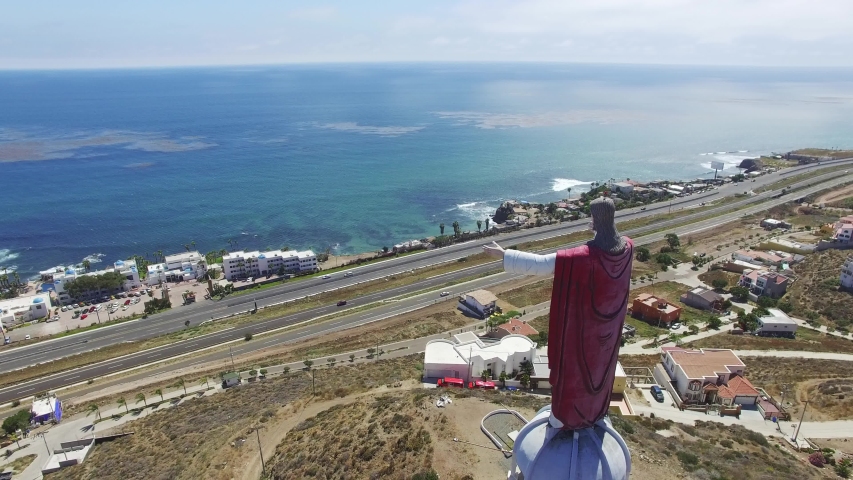 Aerial rotation around Large Jesus Statue in Rosarito Baja California, Mexico looking out to sea.