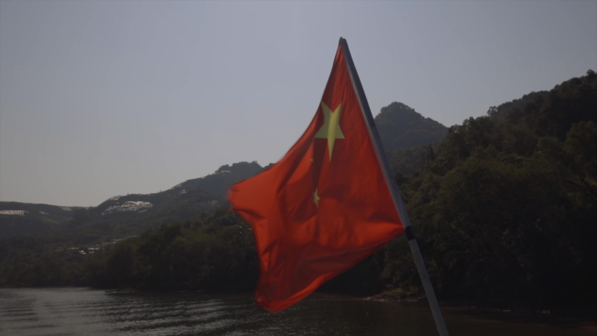 Chinese flag in the wind with rice fields in back, from Guilin, Mainland China on the Li River.