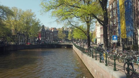 Amsterdam, Netherlands - April, 20, 2019: Amsterdam canal and street with people in spring sunny day.