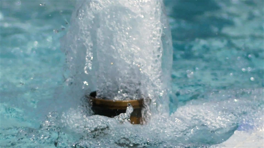 Water drops splashing on water surface in slow motion. Close up of water fountain. Water jet splashing