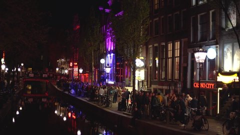 AMSTERDAM,NETHERLANDS-29 APRIL,2019: Crowd of international tourists walking on streets of Red Light District of Amsterdam.Prostitute district - The most popular tourist attraction in Netherlands