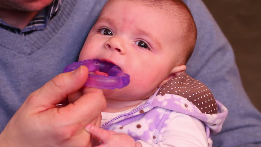 A small baby chews on a teething ring.