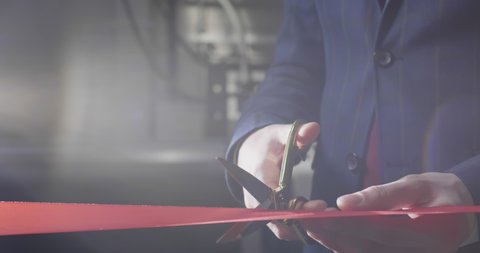 Close up of businessman cutting red ribbon with pair of scissors