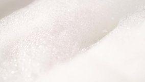 A close-up demonstration video of water pouring into soapy foam and bubbles. Relaxing bath. Spa and wellness concept. Isolated