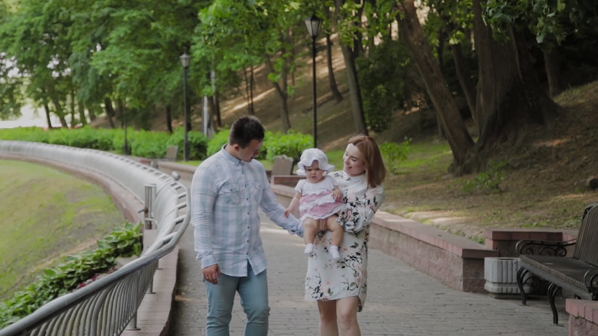 Happy family with a young child walking in the park.