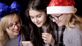 Happy active teens playing smartphones and listening to music celebrating the new year