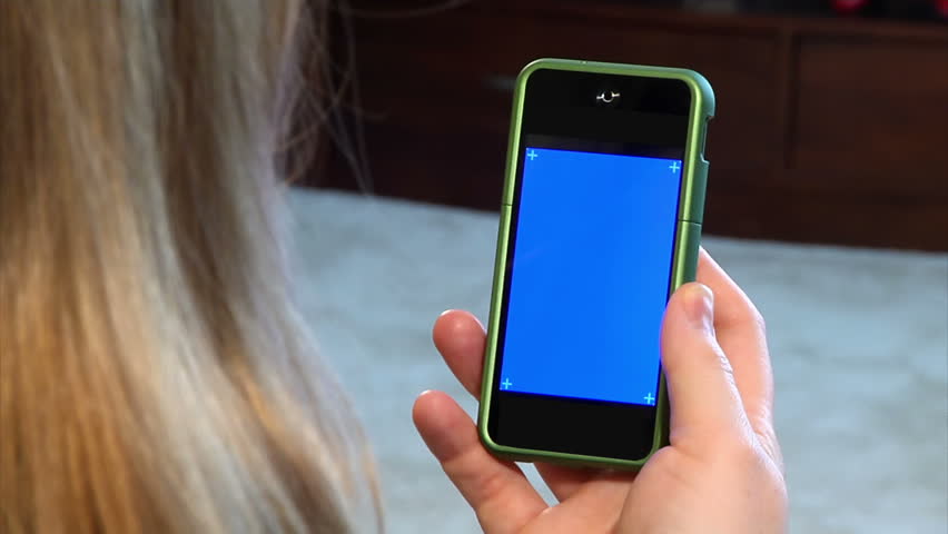 A woman holds a portable cellular telephone.  Bluescreen with corner hashmarks